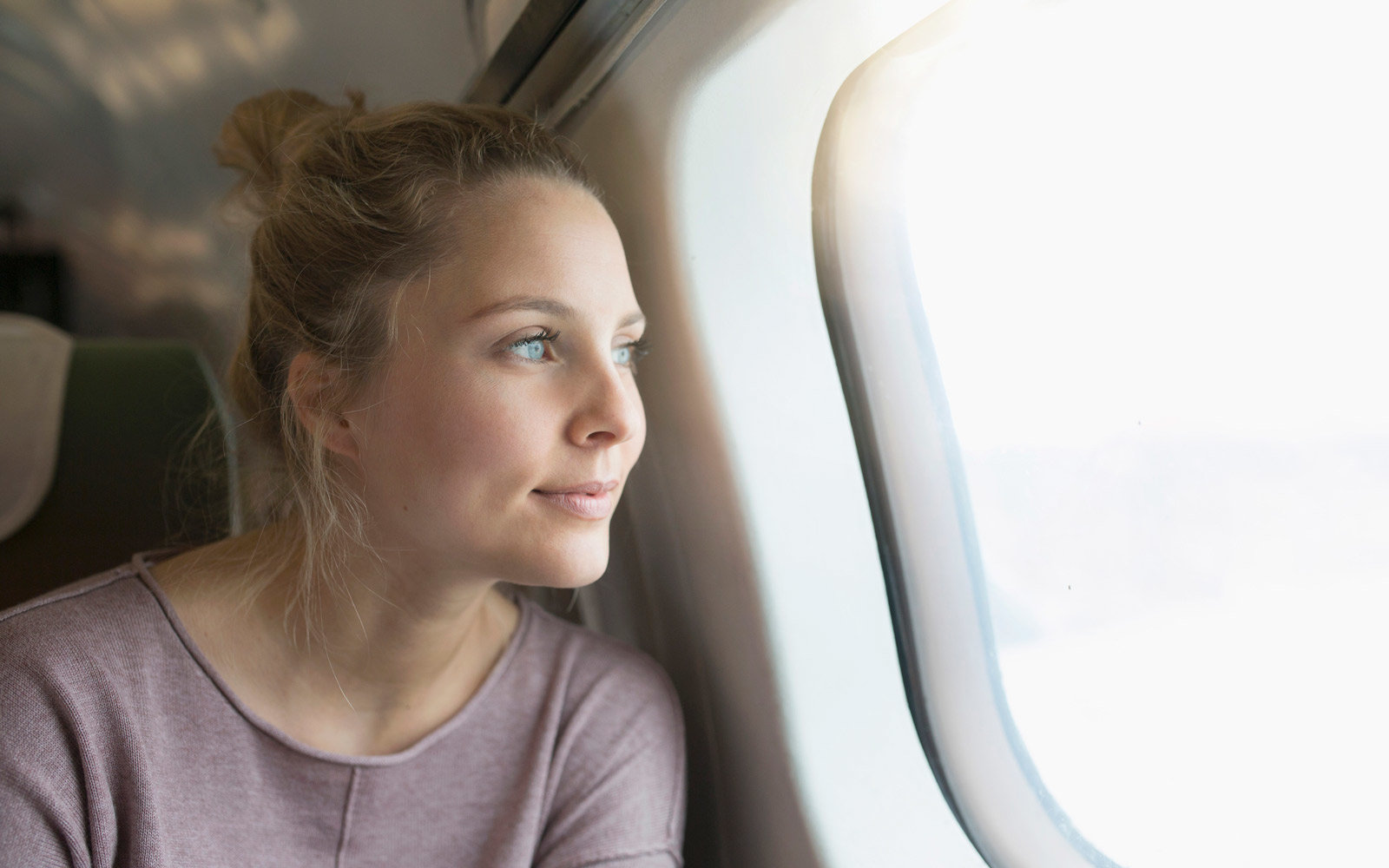 Young woman on airplane, looking out of window